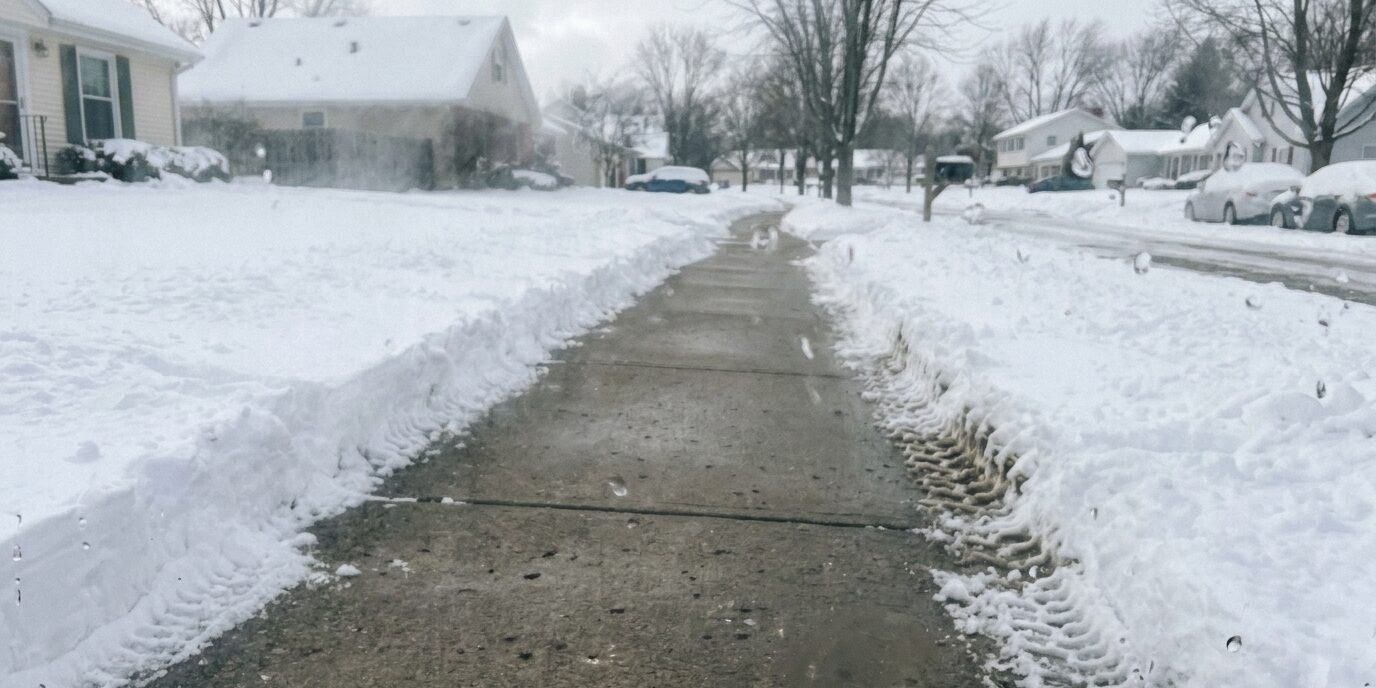 A freshly cleared residential driveway in winter, demonstrating effective home snow plowing and ice prevention by Liberty SoftWash.